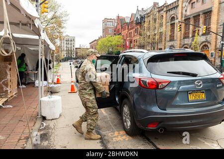 New York, NY - 27. April 2020: Mitglieder der Nationalgarde helfen, während der COVID-19-Pandemie schwarze TLC-Taxiwagen mit Lebensmitteln für ältere und behinderte New Yorker zu laden Stockfoto