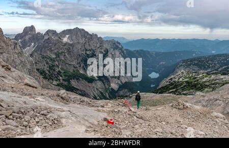 Wanderer auf markiertem Wanderweg von Simonyhütte zur Adamekhütte, felsiges alpines Gelände, Blick auf Bergpanorama und Vorderer Gosausee, Salzkammergut Stockfoto