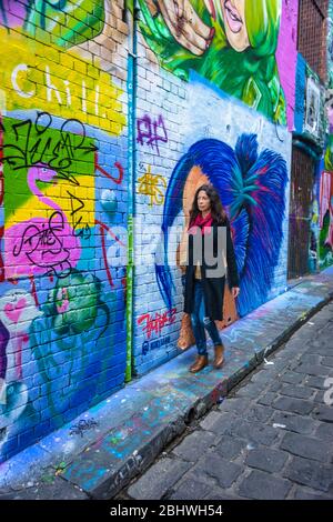 Touristen, die die Hosier Lane entlang laufen, bewundern einen der berühmtesten und beliebtesten Street Art Lane Ways in Melbourne. Stockfoto