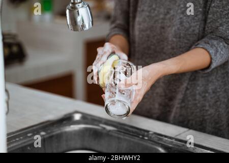 Das Bild einer Frau, die beim Reinigen zu Hause Geschirr abwäscht Stockfoto