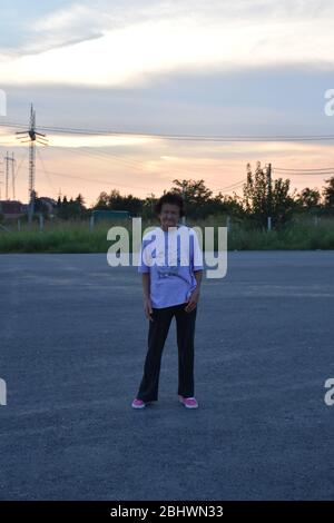 Eine ältere Frau in rosa Sneakers und einem Sportshirt steht im Weg. Stockfoto