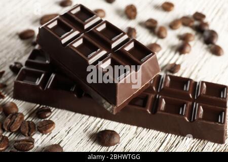 Gefüllte Schokolade mit Kaffeebohnen auf Holztisch, Nahaufnahme Stockfoto