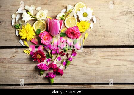 Herz aus schönen Blumen, auf Holztisch Stockfoto