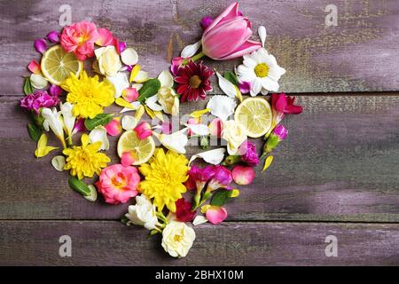 Herz aus schönen Blumen, auf Holztisch Stockfoto