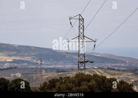 Stromleitungen und Transformatoren. Links ist ein Baum und das Wetter ist bewölkt. Fotografiert im Winter. Stockfoto