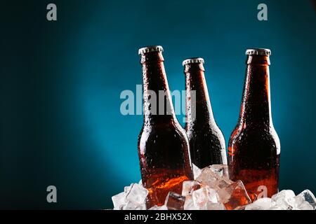 Glasflaschen Bier in Eiswürfeln auf farbigem Hintergrund Stockfoto