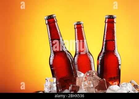 Glasflaschen Bier in Eiswürfeln auf farbigem Hintergrund Stockfoto