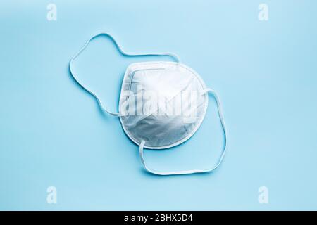 Kn95 Schutzmaske. Weißes Atemschutzgerät auf blauem Hintergrund. Draufsicht. Stockfoto