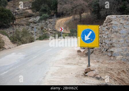 Nahaufnahme des Hinweises für späte Verkehrsbehinderung auf der blauen, weißen linken Seite. Im Hintergrund sind Bäume und Mauern. Stockfoto