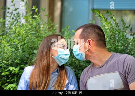 Junges Paar trägt schützende Medizin Maske Blick auf die Augen des anderen Stockfoto