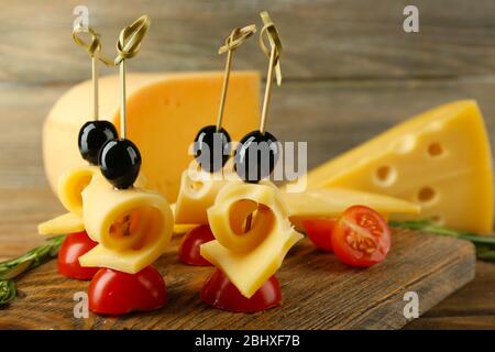 Käsekanaffen mit Kirschtomaten und Oliven auf Holzhintergrund Stockfoto