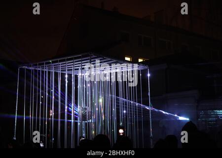 Metallwürfel mit Disco-Kugel innen beleuchtet mit vielen Lichtern um sie herum. Stockfoto