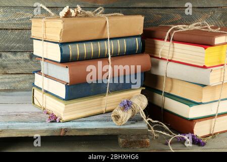 Stapel von Büchern mit trockenen Blumen und Garn auf Holzhintergrund Stockfoto