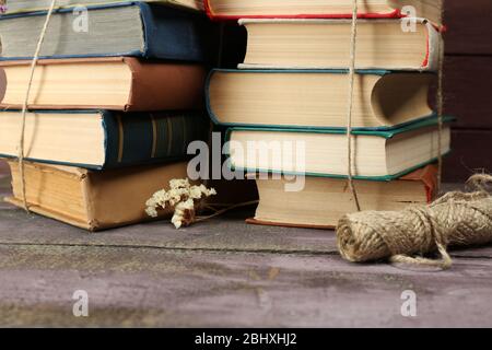 Stapel Bücher mit trockenen Blumen und Garnstrauch auf dem Tisch schließen sich Stockfoto