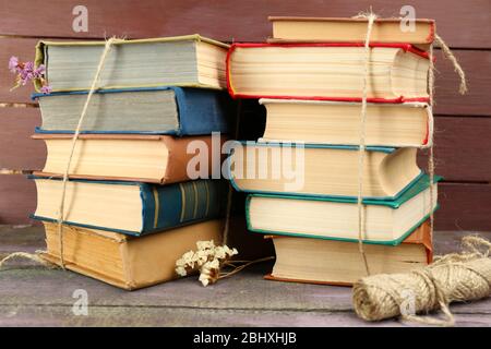 Stapel von Büchern mit trockenen Blumen und Garn auf Holzhintergrund Stockfoto