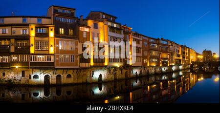 Blick auf den beleuchteten Agout Fluss mit Fransen mit alten Häusern und Brücken in der französischen Stadt Castres in der Abenddämmerung Stockfoto