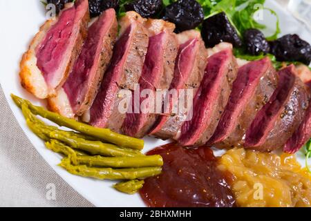 Leckere gegrillte Ente magret Filet mit grünen, Pflaumen, Spargel und Sauce serviert. Stockfoto