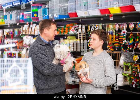 Portrait von positivem Mann und Teenager mit ihren Hunden in einem Tiergeschäft Stockfoto