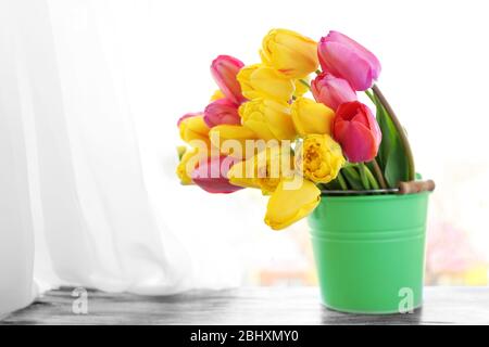 Schöner Strauß Tulpen in Metalleimer auf Fensterbank Stockfoto