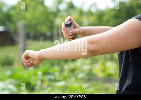 Junge Frau, die Mücke sprüht, Insektenschutz im Wald, Insektenschutz, Helathcare-Konzept Stockfoto