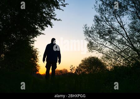 Mann, der bei Sonnenaufgang auf einem Wanderweg neben dem oxford Kanal entlang läuft. Oxfordshire, England. Silhouette Stockfoto