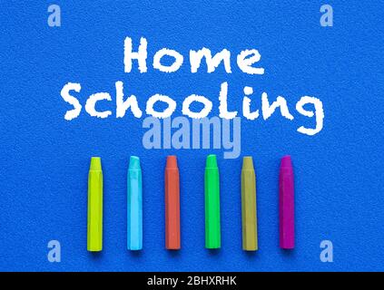 Homeschooling. Wörter oder getippter Text auf blauer Platine. Bunte Buntstifte. Draufsicht. Bildungskonzept. Stockfoto