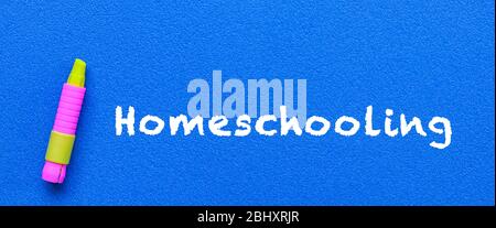 Homeschool. Wörter oder getippter Text auf blauem Brett. Mit gelbem Buntstift. Bildungskonzept. Stockfoto