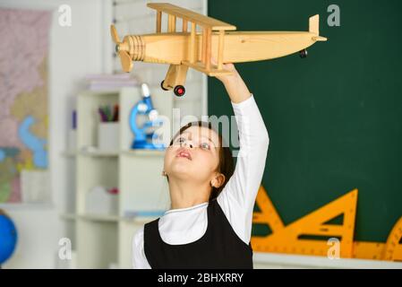 Träumen Sie weiter. Schulmädchen spielen Holz Spielzeug Flugzeug. Fliegen Sie im Flugzeug. Studium der Geographie. Weltweit. Träume vom Reisen. Zurück zur Schule. Geschichte über Sommerferien. Wie ich den Sommer verbrachte. Anreise mit dem Flugzeug. Stockfoto