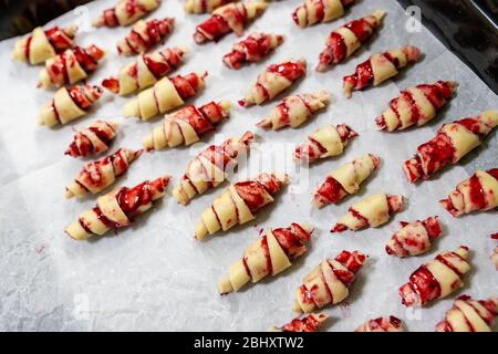 Großmutter, die vor dem Backen in der Küche im Innenbereich handgemachte leckere Butter mit Obst- und Beerenmarmelade auf dem Backblech zubereitet. Rolled Spin hausgemacht Stockfoto