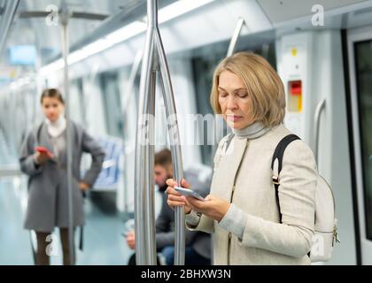 Fokussierte Frau Surfen und tippen Nachrichten auf dem Telefon auf dem Weg zur Arbeit in modernen U-Bahn-Auto Stockfoto
