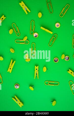 Bürobedarf in Form von farbigen Knöpfen und Büroklammern, Clothepins auf gelbem und grünem Hintergrund, Kopierraum Stockfoto