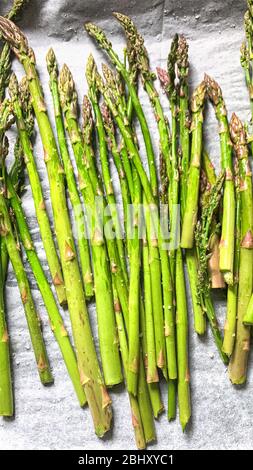 Hausmannskost. Roher Spargel mit Olivenöl und grobem Salz ist auf Backpapier fertig zum Kochen. Stockfoto