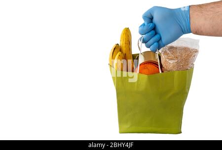 Die Hand mit Gummihandschuhen hält einen Papiertüten mit Lebensmitteln. Lieferung während der Coronavirus COVID-19 Quarantäne. Stockfoto