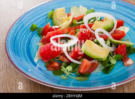 Vitaminsalat aus reifen Wassermelonen, Tomaten, Avocado, Grapefruit und frischem Maissalat auf blauem Teller Stockfoto