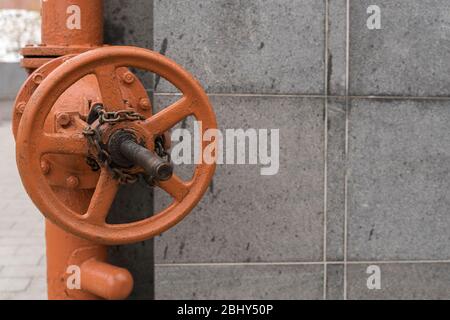 Großes Rohrventil gegen eine graue Ziegelwand Stockfoto