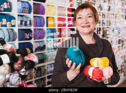 Positive reife weibliche mit bunten Garnen für Ihr Hobby in Handarbeit shop Stockfoto