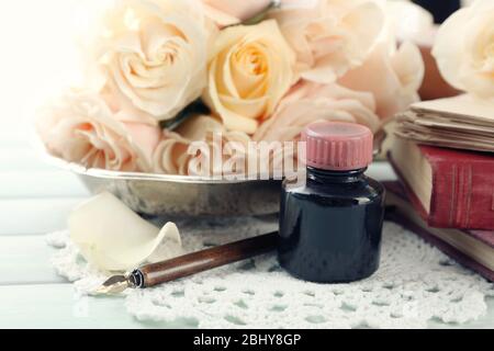 Frische Rosen mit altem Buch und Buchstaben auf farbigem Holztisch Hintergrund. Vintage-Konzept Stockfoto