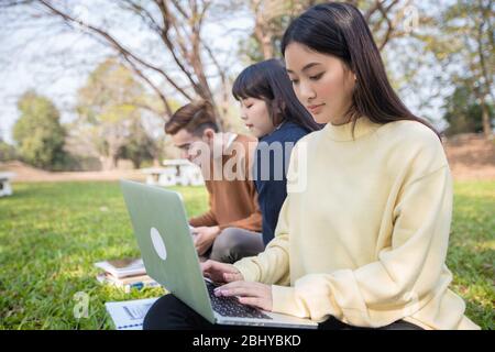 Asiatische Studenten nutzen Notebook-Computer und Tablet, um online im Garten zu Hause während der Coronavirus-Epidemie und Quarantäne zu Hause zu arbeiten und zu studieren Stockfoto