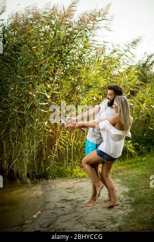 Schönes junges Paar genießen Angeln auf dem See an sonnigen Sommertag Stockfoto