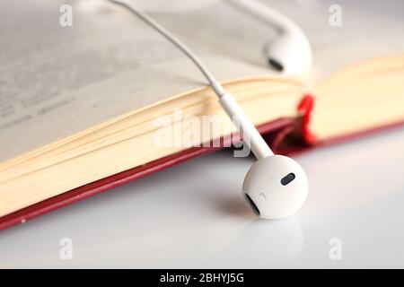 Kopfhörer und Buch auf dem Tisch, Nahaufnahme Stockfoto