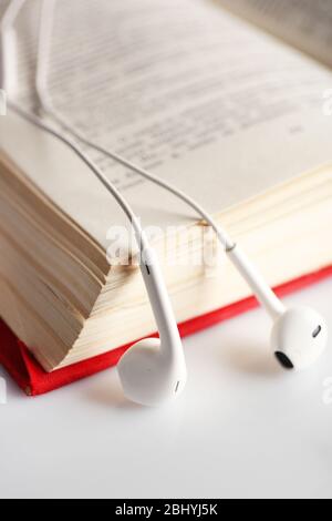 Kopfhörer und Buch auf dem Tisch, Nahaufnahme Stockfoto