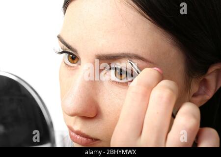 Junge Frau pflückt Augenbrauen mit Pinzette aus der Nähe Stockfoto