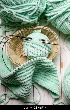 Garnrollen im Korb mit Stricknadeln.Skeins aus Wolle und Stricknadeln auf einem hölzernen Hintergrund Stockfoto