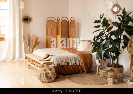 Modernes Interieur-Design. Weiße und beige Decken auf einem bequemen Bett im Boho Schlafzimmer Interieur exotisches Schlafzimmer Interieur, skandinavischen Stil.Texturiert Stockfoto