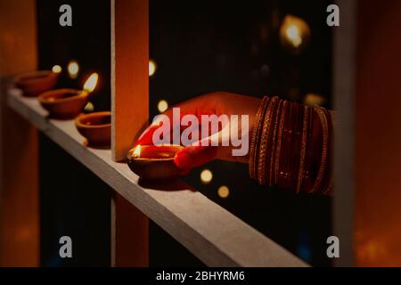 Junge Frau, die anlässlich von Diwali Diyas auf den Holzrahmen setzt. Stockfoto