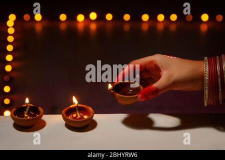 Junge Frau, die anlässlich von Diwali Diyas auf das Geländer legt. Stockfoto