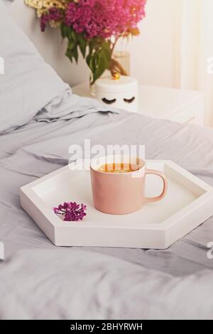 Tablett mit frischer Tasse Kaffee und Macarons Dessert stehen auf dem Bett Stockfoto