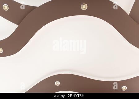 Stretch-Decke in hellbrauner Farbe mit Lampen. Stockfoto