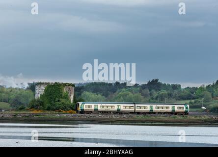 Fota Island, Cork, Irland. April 2020. Ein Pendlerzug am frühen Morgen vom Bahnhof Kent nach Cobh fährt am Mortello Tower auf Fota Island in Co. Cork, Irland, vorbei. - Credit; David Creedon / Alamy Live News Stockfoto