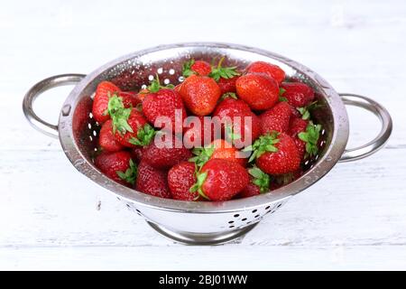 Reife Erdbeeren in Sieb auf Holztisch, Nahaufnahme Stockfoto